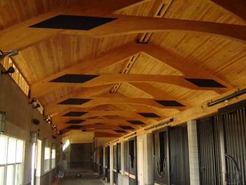 Luxury barn interior featuring natural wood tongue-and-groove ceiling with decorative black metal beams in chevron pattern