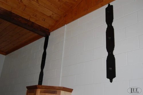 Black decorative metal finial or chain hardware piece suspended from natural wood ceiling beam