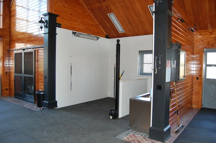 White interior room with black vertical bar partition walls creating enclosed stall area with white ceiling