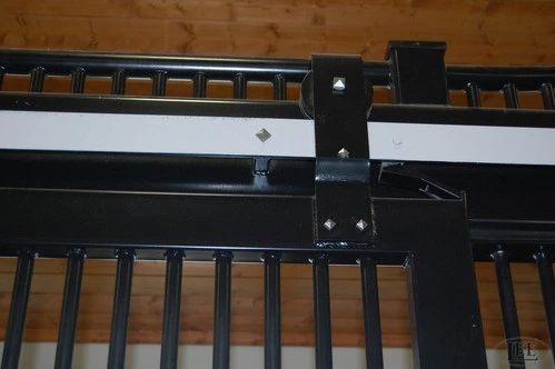 Close-up detail of black metal sliding door track hardware and roller mechanism on natural wood ceiling