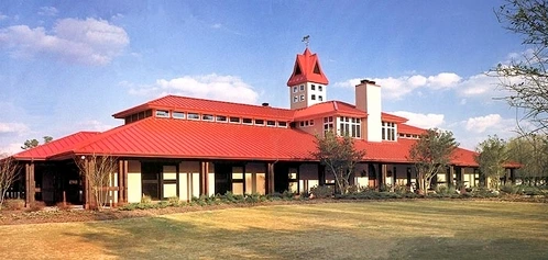 Long red metal roof barn with cream walls, multiple cupolas and transom windows along length