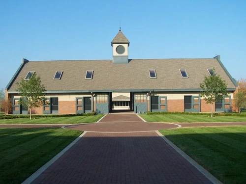 Tan barn with cupola, center breezeway opening and symmetrical design on paved driveway