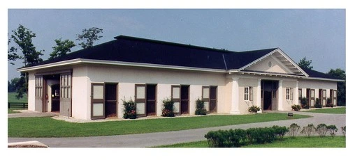 White stucco barn with black shutters and multiple arched window openings on green lawn