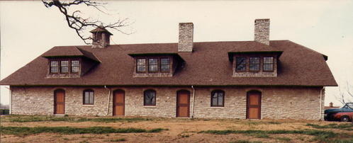 Stone barn with dual levels, brown roofs and natural landscape setting