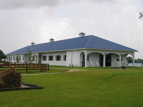 White stucco barn with gray roof, arched openings and green lawn setting