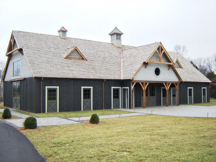 Dark gray barn with timber-frame gable details, white trim and manicured lawn