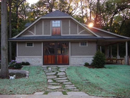 Gray barn with timber-frame porch and mahogany sliding doors in evening light