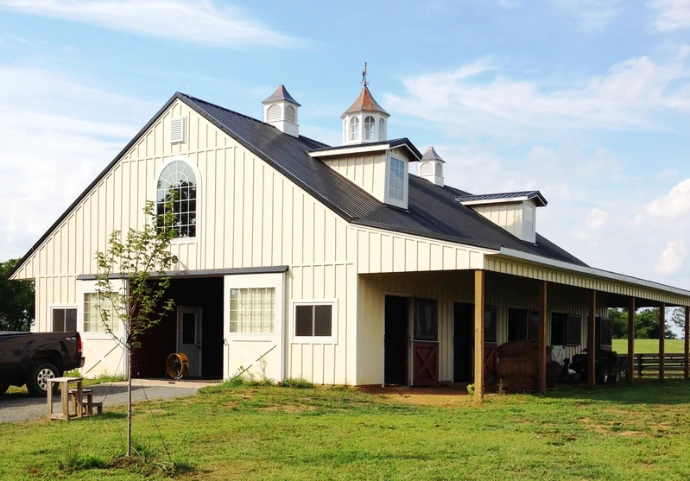 Cream barn with gray roof, cupolas and covered breezeway in rural setting