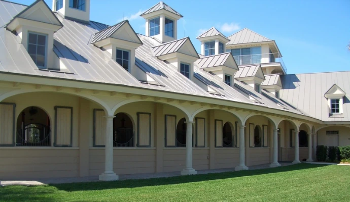 White stucco barn with arched openings, balcony railings and multiple roof dormers