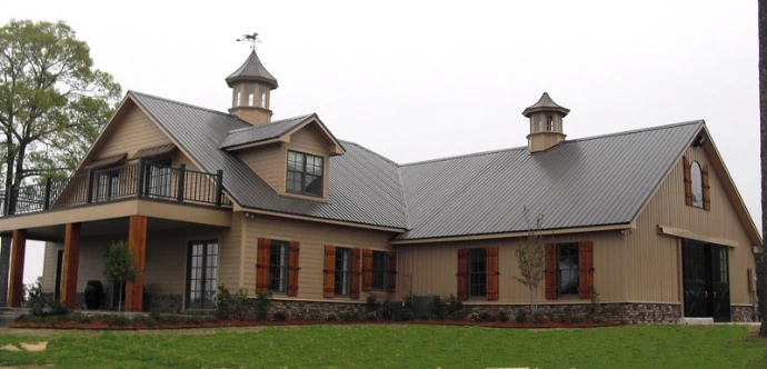 Tan stucco barn complex with multiple cupolas and covered walkway areas
