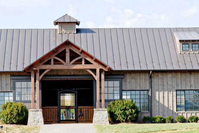 Timber-frame barn with stone pillars, metal roof and cupola viewed from entrance
