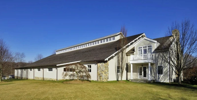 White barn with stone accents, timber-frame gable and symmetrical stall openings