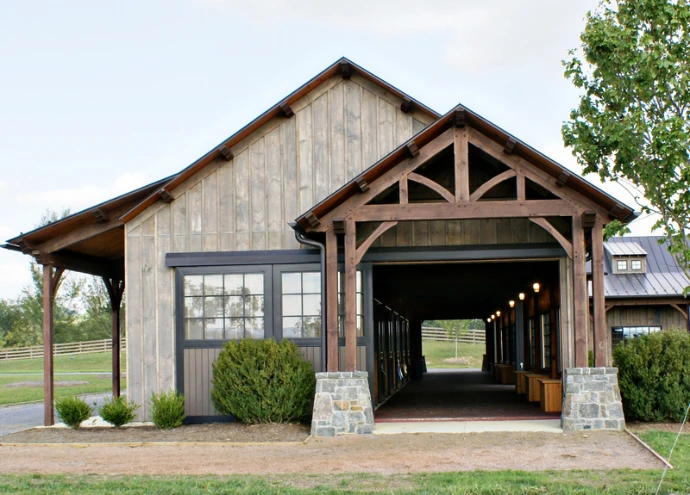 Timber-frame barn with weathered wood siding, stone pillars and covered entrance breezeway