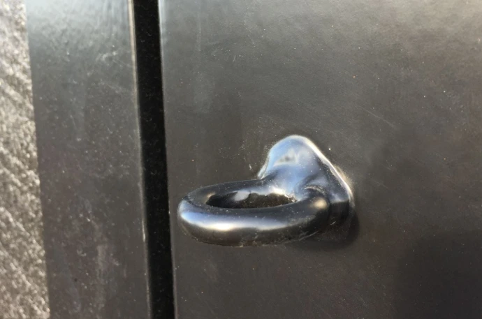 Tie Back Ring: Metal hook latch hardware mounted on dark metal door panel