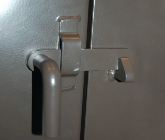 Door Handle Close-up: Grey curved lever handle mounted on gray metal door panel