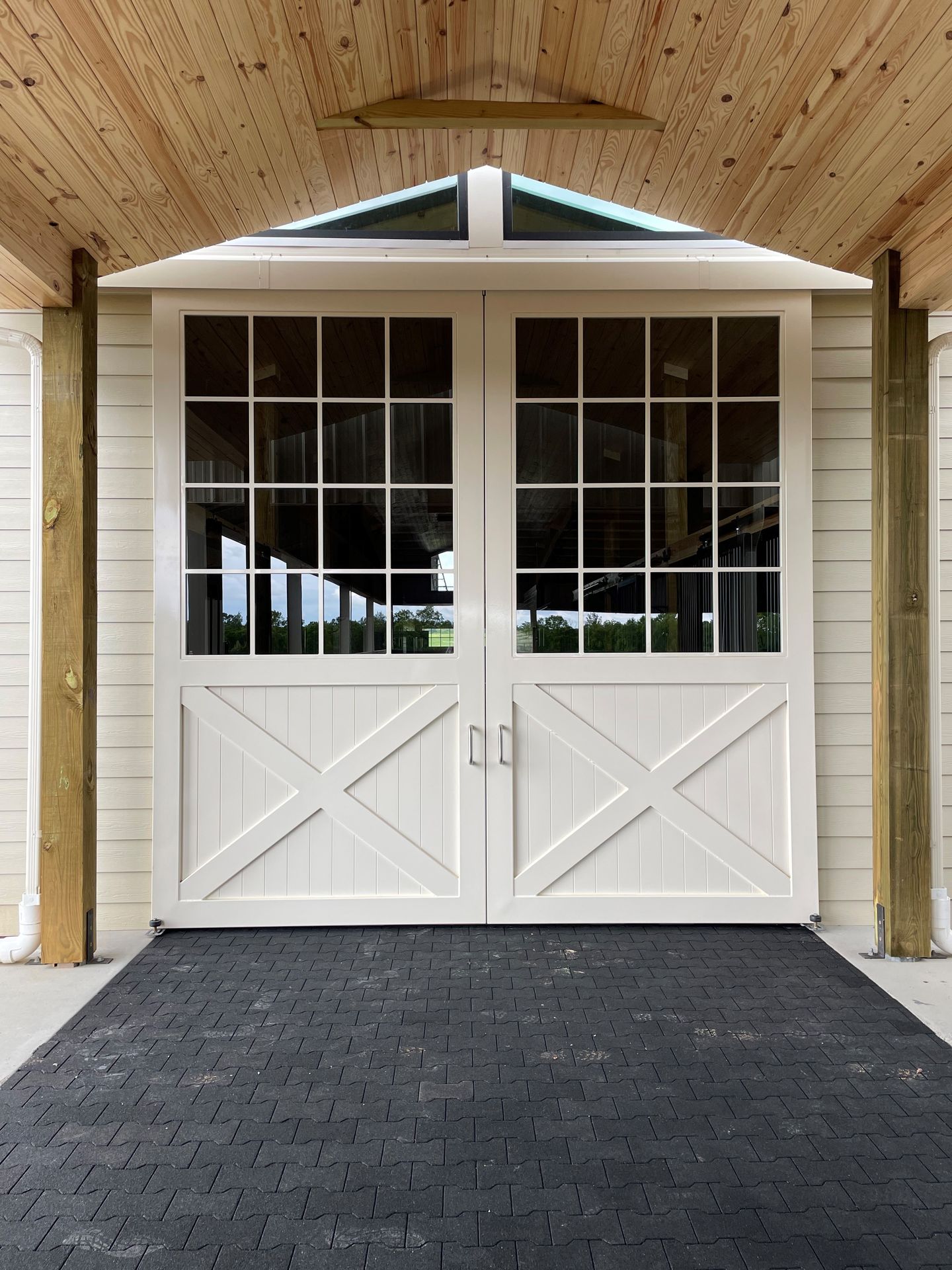 A V-Groove Panel Upgrade featured on a white barn double-door with dark pathway and wooden overhang.