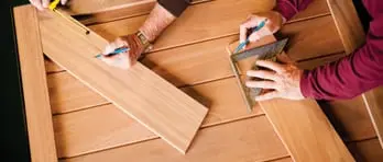 Since 1981: Overhead view of hands packing cardboard boxes with bubble wrap and shipping materials in warehouse setting
